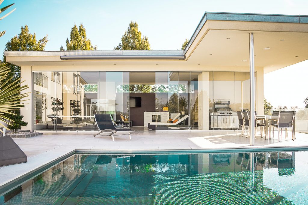 The photo displays a modern style home with a white colored exterior and a pool.