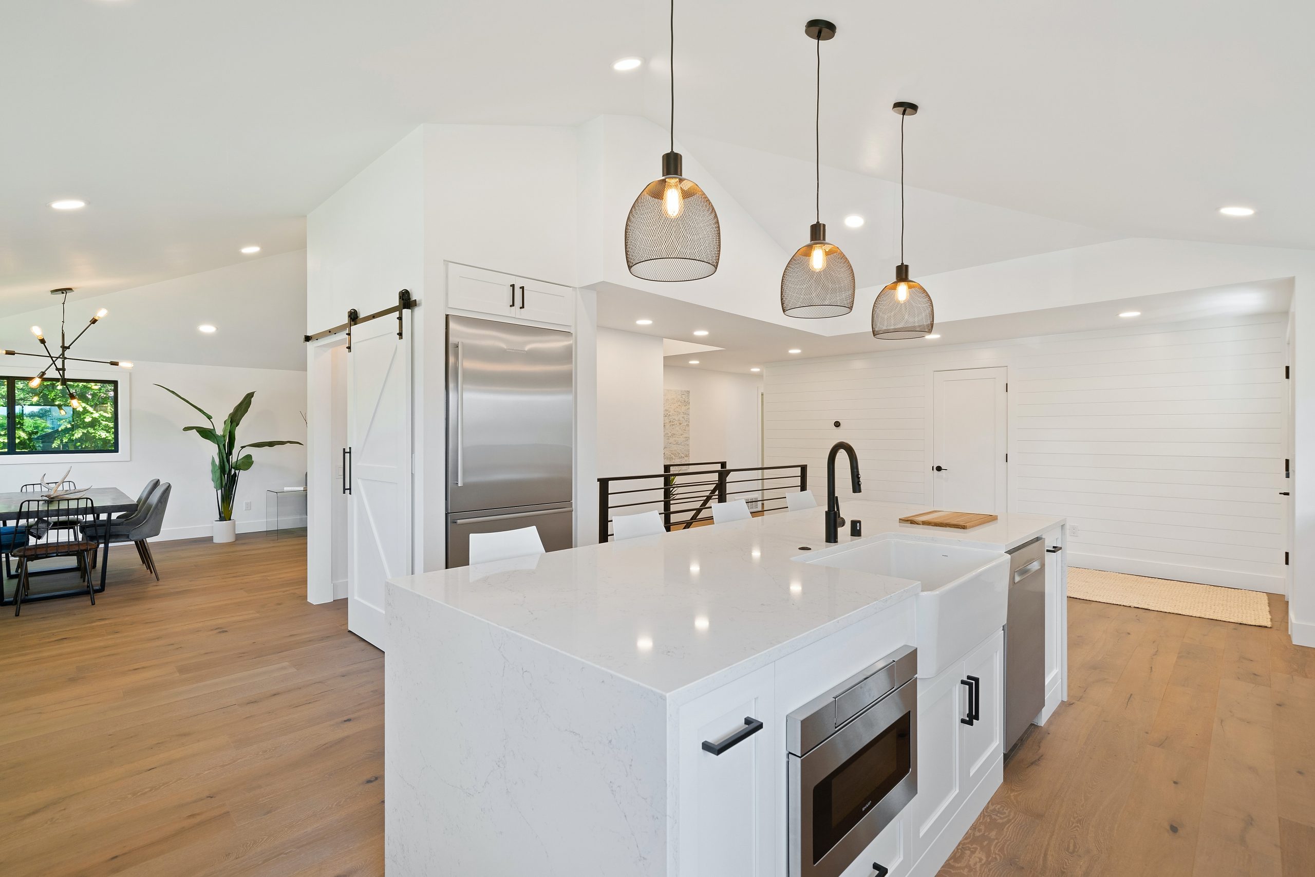 The image features a shiny white kitchen counter with three pendant lights overhanging the counter.